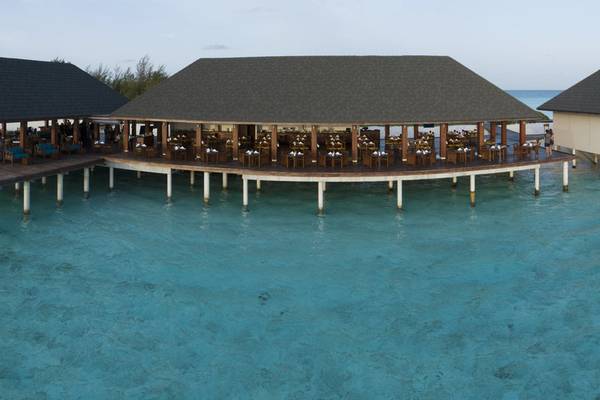 Luftaufnahme des Summer Island Maldives Hotels mit Restaurant am Wasser und Gästen.