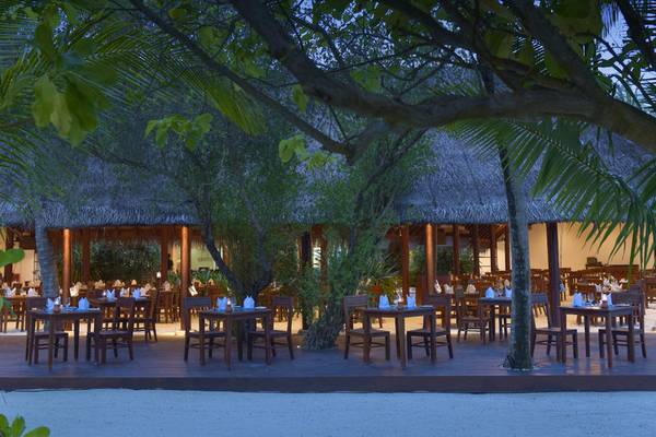 Außenbereich des Restaurants im Summer Island Maldives Hotel mit gedeckten Tischen und tropischen Bäumen.