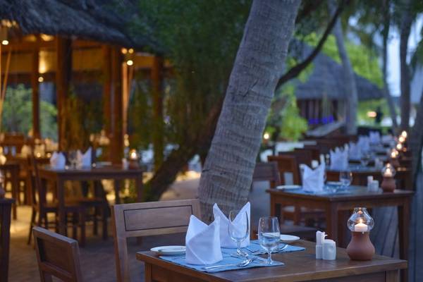 Außenbereich des Summer Island Maldives Resorts mit gedeckten Tischen und Kerzen.