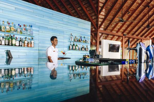 Ein Barkeeper im Summer Island Maldives Hotel serviert ein Getränk an der Theke.