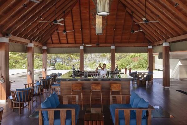 Innenansicht der Bar im Summer Island Maldives Hotel mit Holzmöbeln und Deckenventilatoren.