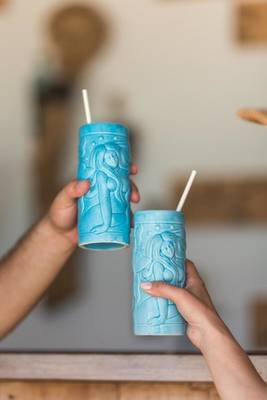 Zwei Personen halten türkisfarbene Becher mit Strohhalmen.