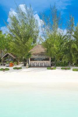 Strandansicht des Summer Island Maldives Hotels mit einer Bar und Wassersportgeräten.
