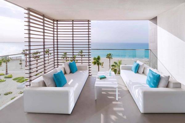 Terrasse mit Meerblick im Nikki Beach Resort & Spa Dubai, mit weißen Sofas und blauen Kissen.