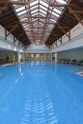 Ein großer Innenpool im Turquoise Hotel mit einer Glasdecke und Liegestühlen.