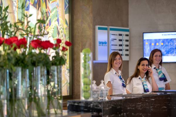 Empfangsmitarbeiter im Turquoise Hotel stehen hinter der Rezeption und sprechen am Telefon.