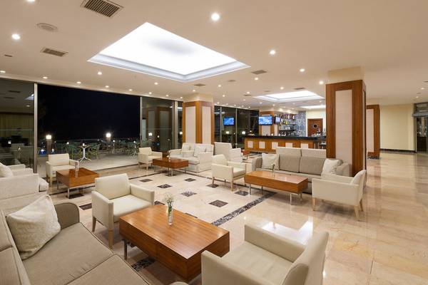 Lobbybereich des Turquoise Hotels mit hellem Interieur, modernen Möbeln und Blick auf die Nachtlandschaft.