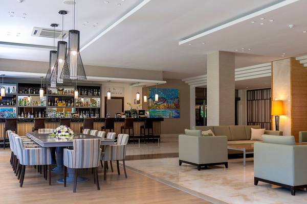 Lobby-Bar-Lounge-Bereich im Turquoise Hotel mit Tisch, Stühlen, Sofas und einer Bar.