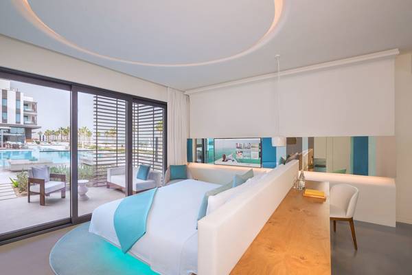 Schlafzimmer im Nikki Beach Resort & Spa Dubai mit großem Bett, Aussicht auf Pool und Garten.