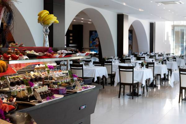 Innenansicht des Restaurants im Turquoise Hotel mit Dessertbuffet und gedeckten Tischen.