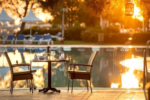 Turquoise Hotel Pool Tisch am Abend mit Sonnenuntergang im Hintergrund.