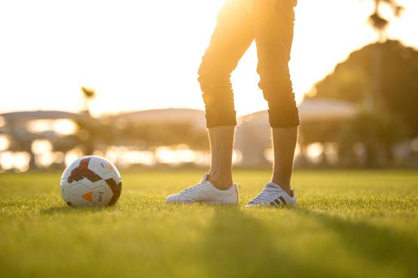 Mann mit Fußball im Stadion, bei Sonnenuntergang
