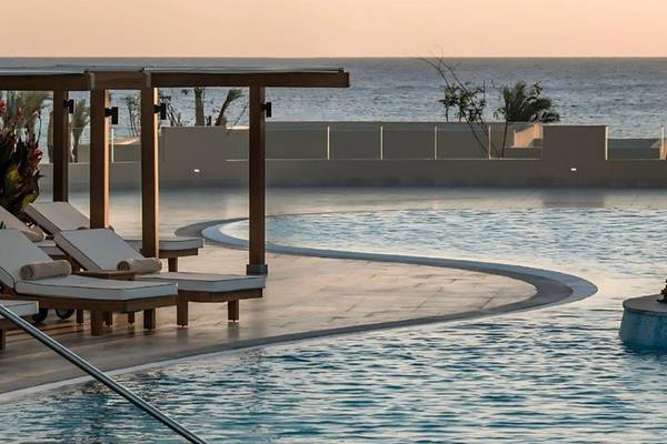 Poolbereich des JAZ Riviera Hotels bei Sonnenuntergang mit Loungestühlen und Meerblick.