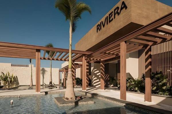 Außenansicht des JAZ Riviera Hotels mit einem großen Palmbaum vor der Eingangstür.