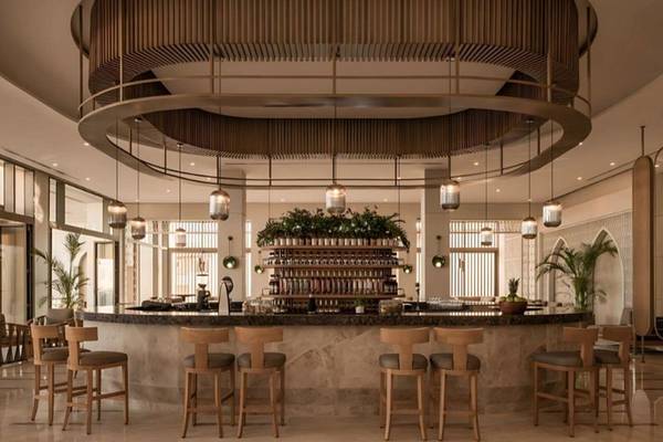Innenansicht der Bar im JAZ Riviera Hotel mit kreisförmigem Kronleuchter und Holzstühlen.