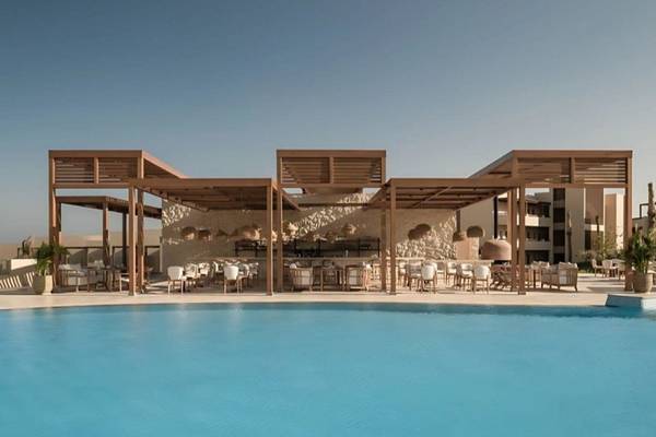 Pool-Lounge-Bereich im JAZ Riviera Hotel mit braunen Überdachungen und weißen Stühlen.