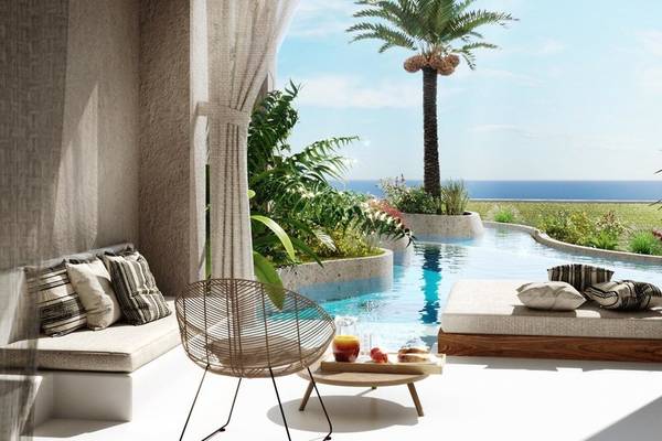 Terrasse im JAZ Riviera Hotel mit Blick auf das Meer, gesäumt von Pflanzen und einem Infinity-Pool.