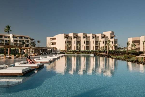 Poolbereich des JAZ Riviera Hotels mit Liegen und Gebäuden im Hintergrund.