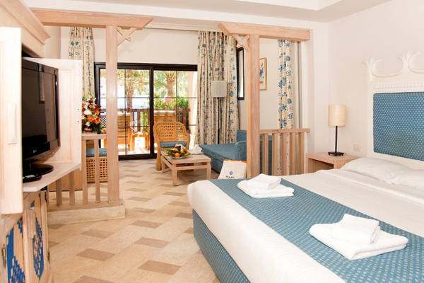 Innenansicht eines Zimmers im Grand Hotel Sharm El Sheikh mit Bett, Fernseher und Balkon.