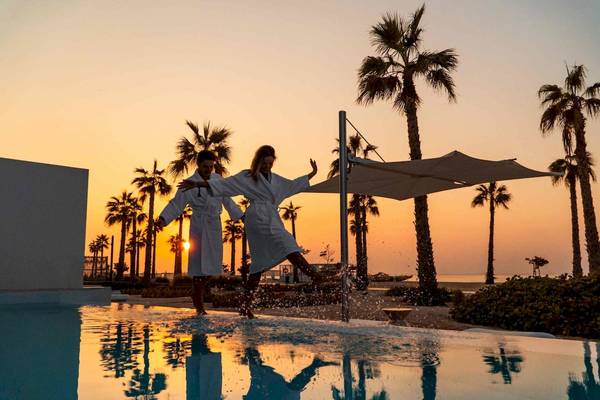 Zwei Leute springen im Pool bei Sonnenuntergang im Nikki Beach Resort & Spa Dubai.