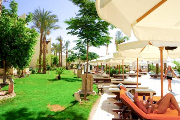 Eine Frau liegt auf einem orangefarbenen Liegestuhl im Freien des Grand Hotel Sharm El Sheikh.