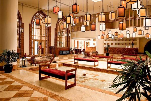 Lobby des Grand Hotel Sharm El Sheikh mit hängenden Lampen, Bänken und Pflanzen.