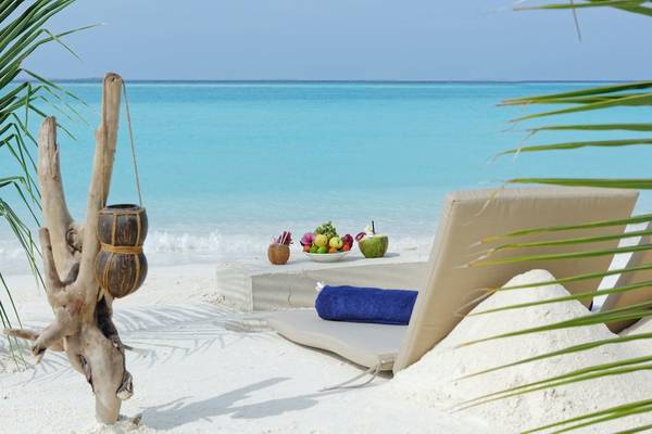 Ein Strand mit Liegen, Früchten und einer Kokosnuss an einem ruhigen Tag.