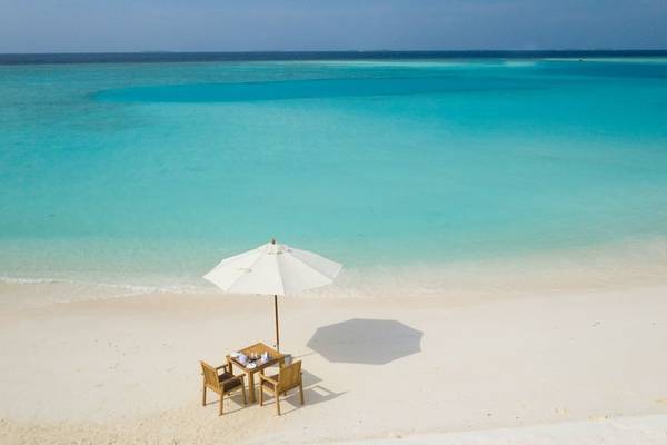 Ein Tisch mit einem Schirm auf dem Strand des Brennia Kottefaru Maldives.