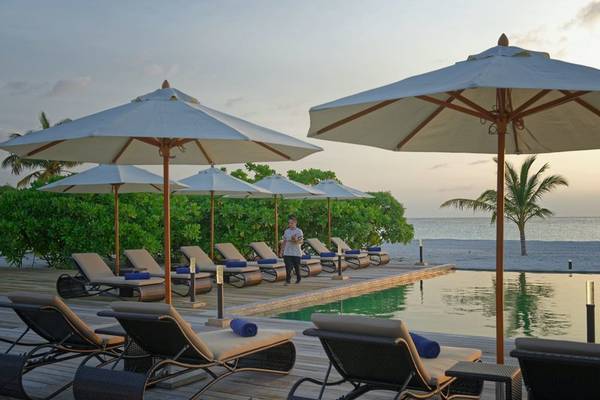 Außenbereich des Brennia Kottefaru Maldives Hotels mit Pool, Liegen und Sonnenschirmen am Meer