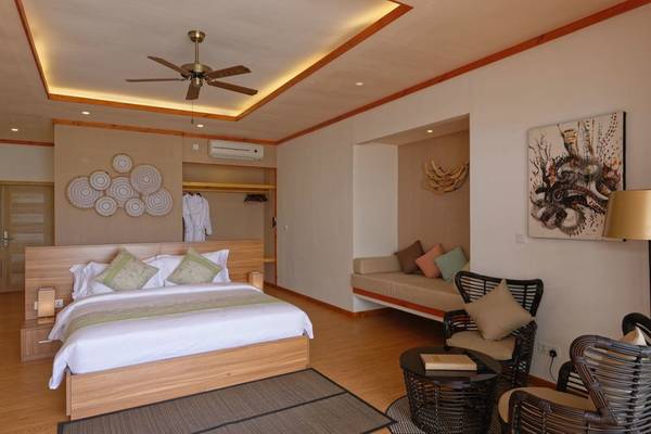 Innenansicht des Schlafzimmers im Brennia Kottefaru Maldives Hotel mit einem großen Bett, Möbeln und einer Klimaanlage.