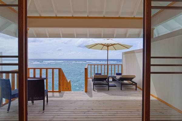 Terrasse des Brennia Kottefaru Maldives mit Blick auf das Meer und eine offene Tür.