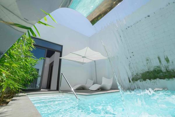 Außenpool mit Wasserfall und weißen Liegestühlen im Nikki Beach Resort & Spa Dubai
