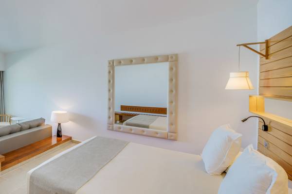 Hotelzimmer mit einem Bett, Spiegel und Sofa in einem modernen Design.