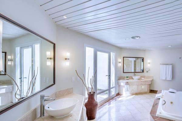 Ein Badezimmer mit Badewanne, Spiegel, Waschbecken und Türen zum Patio im Paradisus Varadero Resort & Spa.