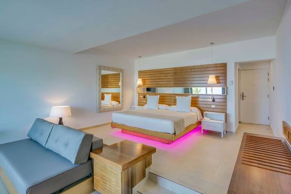 Schlafzimmer im Paradisus Varadero Resort & Spa mit großem Bett, Holzkopfteil und pinkem LED-Licht.