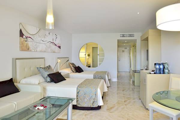 Suite-Schlafzimmer im Paradisus Varadero Resort mit zwei Betten, weißem Sofa und Glastisch.