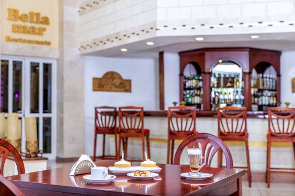 Innenansicht des Bella Mar Restaurants mit Tisch, Kaffee und Gebäck auf dem Tisch.