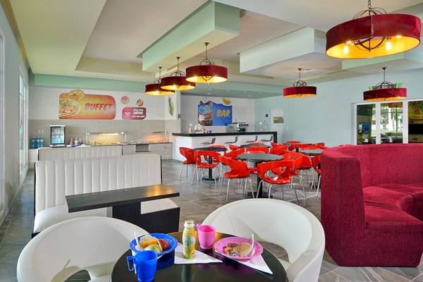 Innenansicht des Restaurants im Paradisus Varadero Resort & Spa mit roten Stühlen und Tischen, weißen Bänken, und bunten Speisen auf dem Tisch.