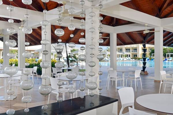 Innenpoolbereich des Paradisus Varadero Resort & Spa mit weißen Tischen und Stühlen.
