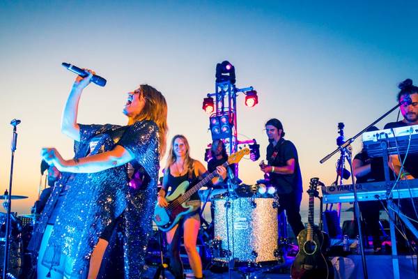 Ibizahouse Orchester Auftritt bei Sonnenuntergang mit Sängerin, Gitarristen und Schlagzeugern.