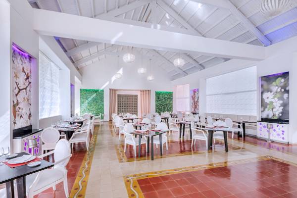 Innenansicht eines weißen Restaurants mit modernen Möbeln und hängenden Lampen.