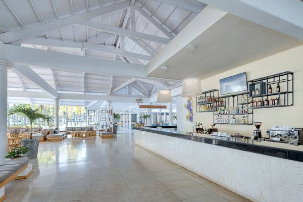 Die Bar im Paradisus Varadero Resort & Spa mit weißer Theke, modernen Möbeln und einer Flaschenwand.