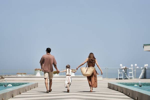 Eine Familie geht am Pool des Arina Beach Resorts spazieren.