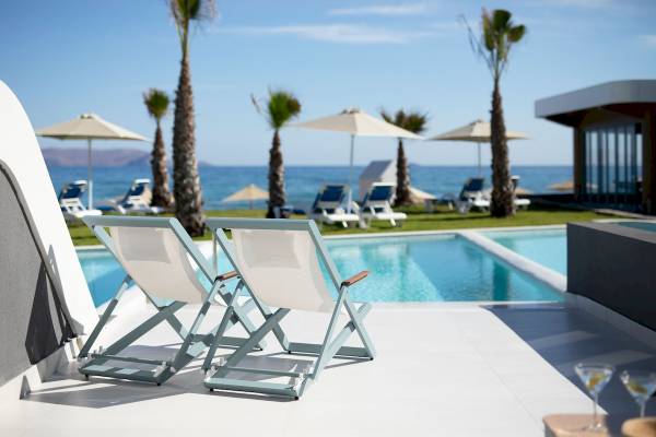 Zwei Liegestühle am Pool des Arina Beach Resorts mit Blick auf das Meer.