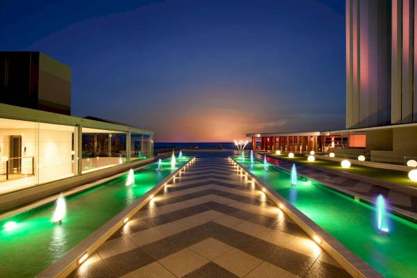 Der beleuchtete Eingangsbereich des Arina Beach Resorts bei Nacht.