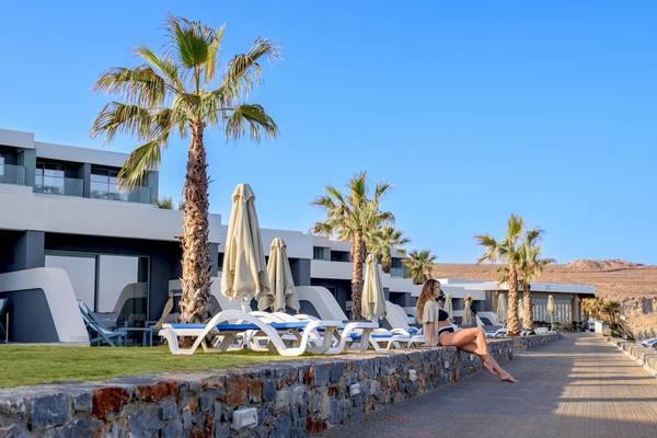 Eine Frau sitzt auf einer Mauer vor dem Arina Beach Resort Hotel.