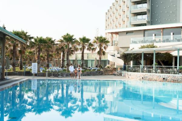 Familie steht am Pool des Arina Beach Resorts vor einem Hotelgebäude