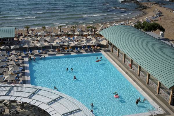 Luftaufnahme des Arina Beach Resort Pools und Strands mit vielen Gästen und Sonnenschirmen.