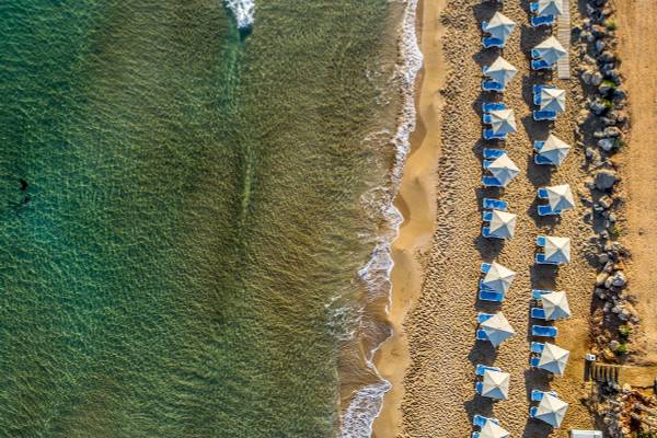 Luftaufnahme des Arina Beach Resorts Strands mit Sonnenschirmen und kristallklarem Wasser