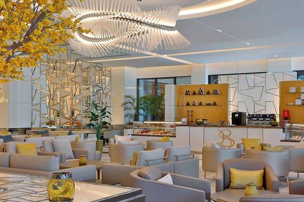 Innenansicht des Hilton Dubai Palm Jumeirah Lounges mit modernen Möbeln, gelben Kissen und einer großen Lampe.